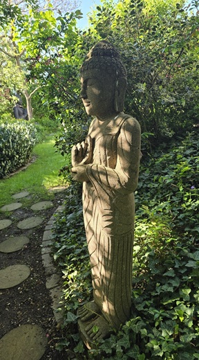 Stehender Buddha im günen Garten